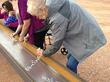 Community members signing beam